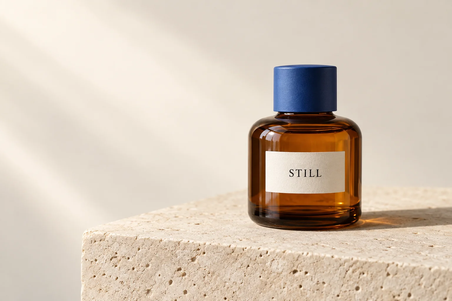 Amber glass bottle with a blue cap and STILL label on a limestone plinth